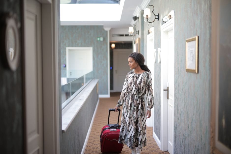 A woman with a suitcase arriving at a hotel in daylight
